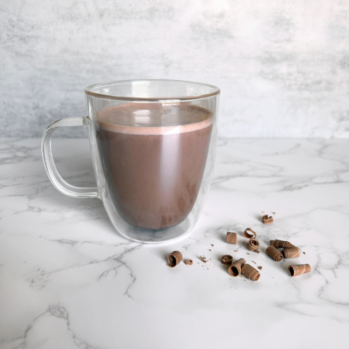 Metabolic Web Store MRC Creamy Hot Chocolate Protein Drink in a clear mug with chocolate shavings surrounding it